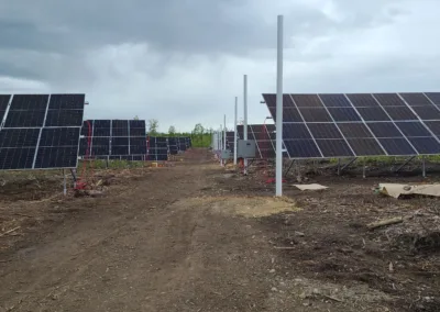 Solar panels on a dirt road under a cloudy sky.