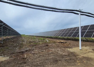 Solar panels in a field under a cloudy sky.